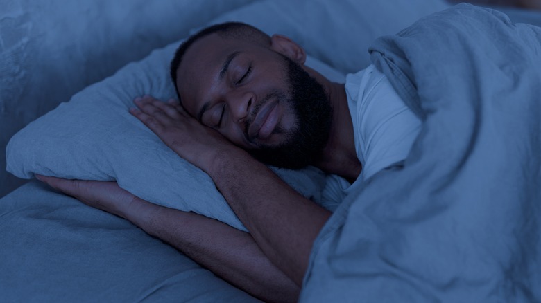 Sleeping man smiling in dark room