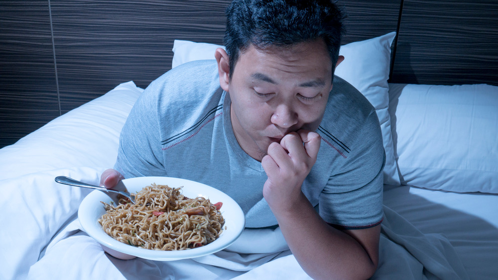 Man eating at night in bed
