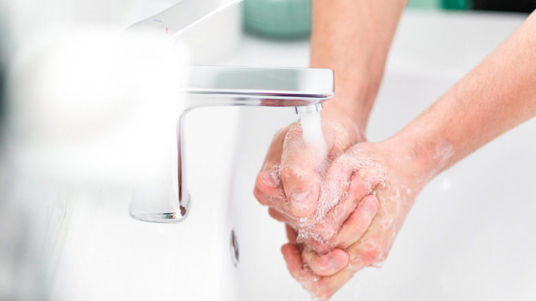 Washing hands under running faucet