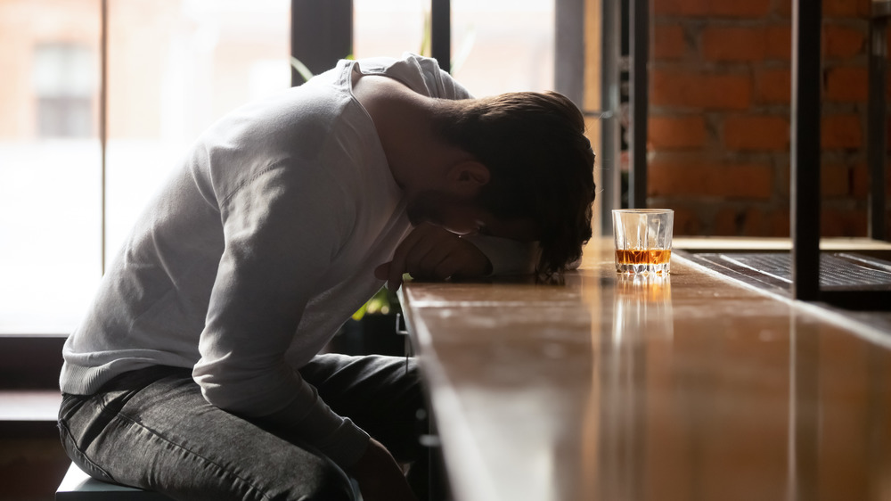 depressed young man at an empty bar with a drink 
