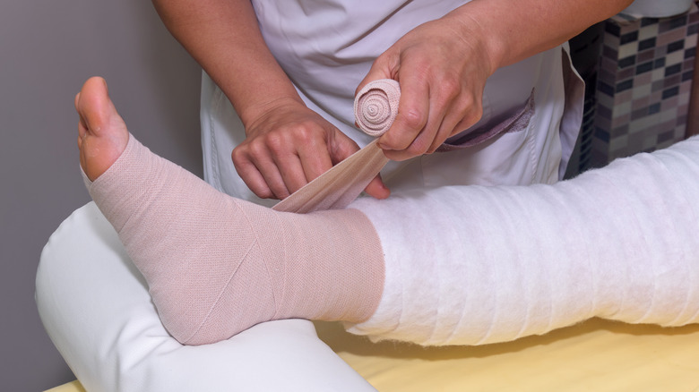 Nurse wrapping bandage on leg