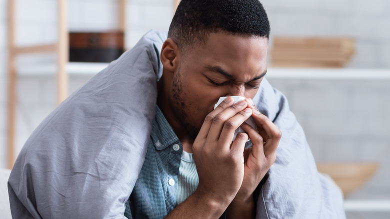 Sick man blowing nose