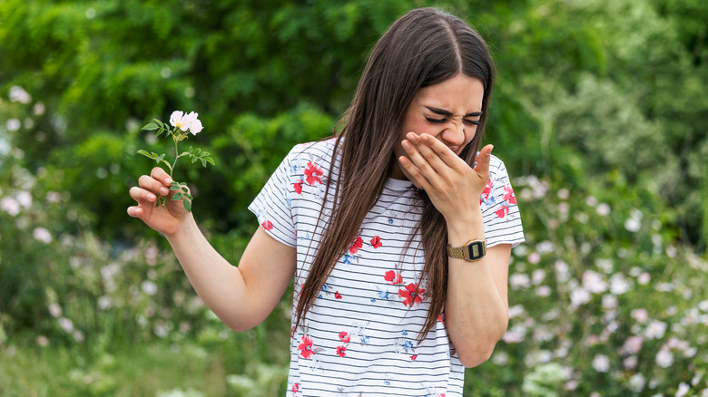 woman holding flower and sneezing