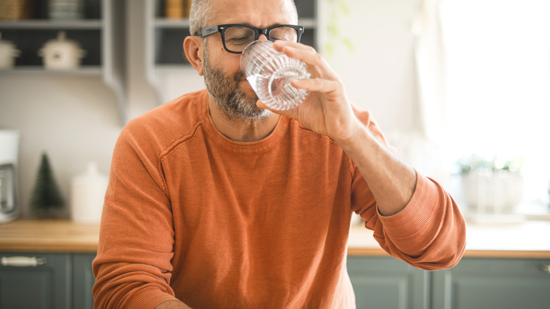 man drinking water in kitchen