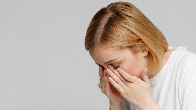 Blonde white woman rubbing her eyes