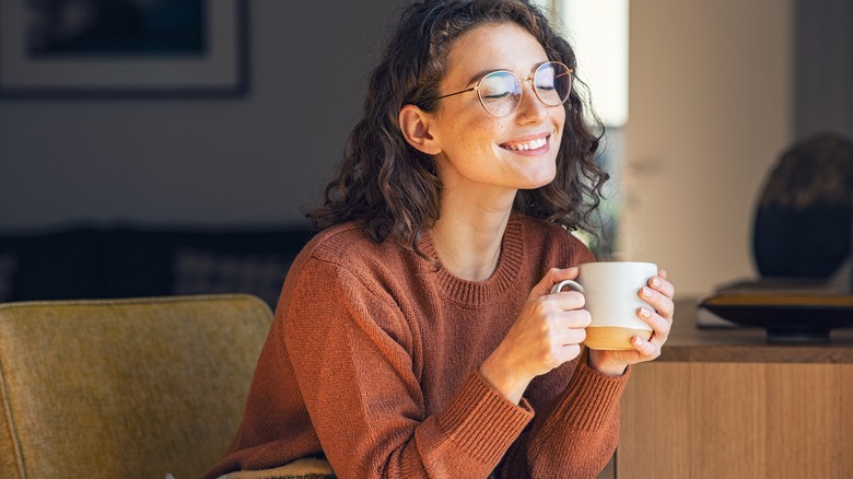 a woman happily drinking from a  mug