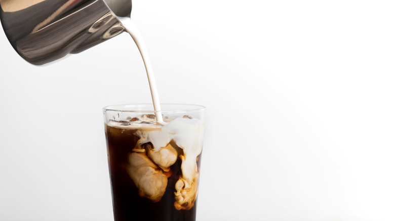 dairy-free milk being poured over coffee 