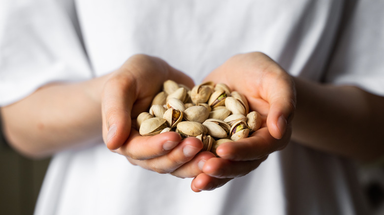 A woman holds a handful of pistachios