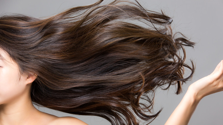 A woman tosses her long healthy hair