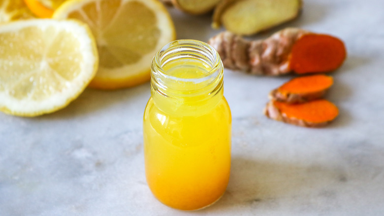 Ginger shot surrounded by fruits 