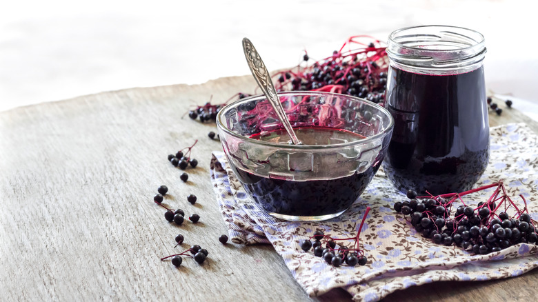 Elderberry bunches in bowls, with bottled juice