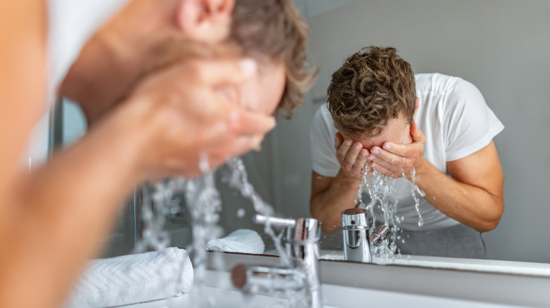 Reflection of man washing his face in the mirror