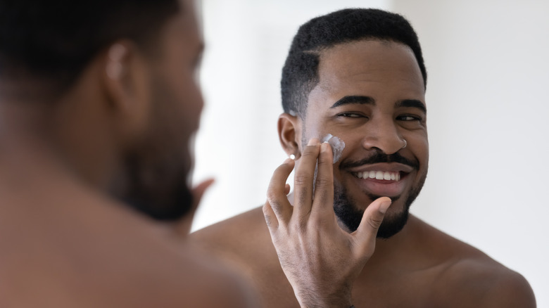 smiling black man moisturizing skin