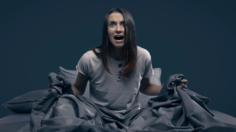 Scared woman waking up from a bad recurring dream