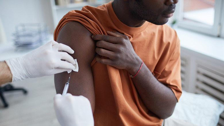 Gloved hands inserting needle in arm