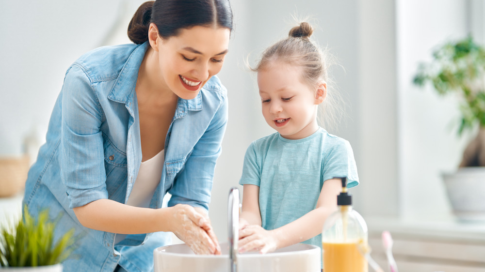 A woman and a little girl wash their hands