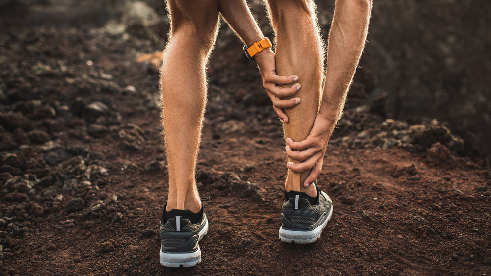 man holding calf during cramp