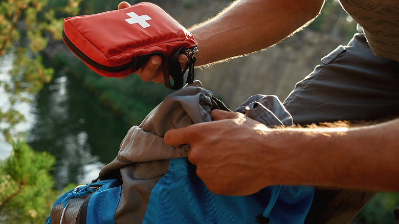 Man pulling first aid kit out of a backpack
