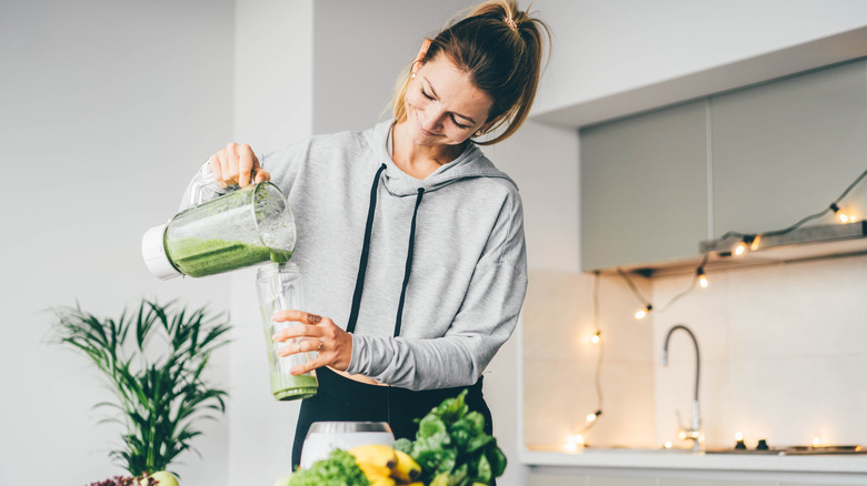 A woman pours a green smoothie