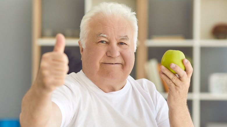 senior man holding an apple 