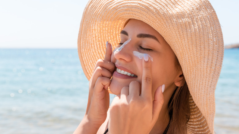 A woman applies sunscreen to her face