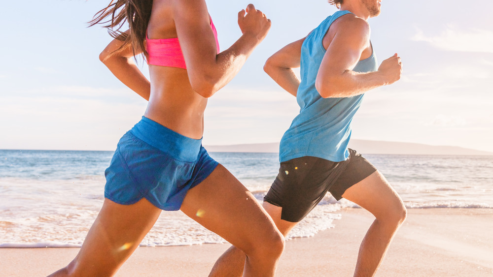 man and woman running on beach