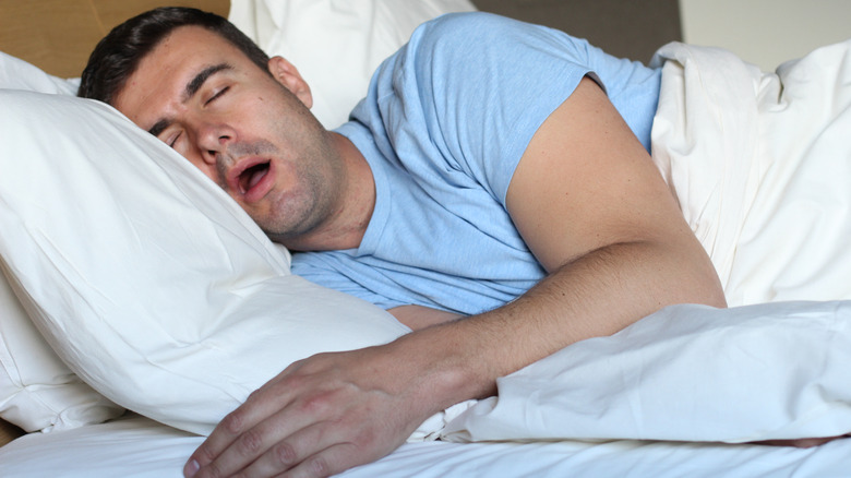 Man sleeping on his side in bed with mouth hanging open