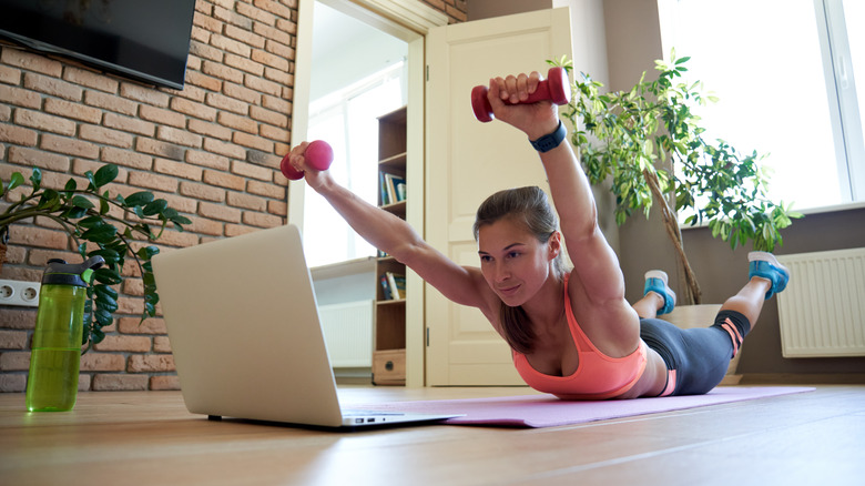 young woman lying on her stomach, following a virtual fitness class