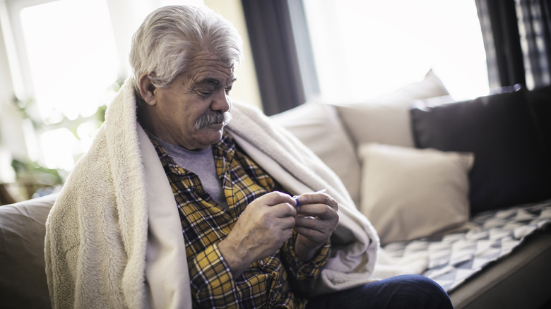 Sick man holding thermometer