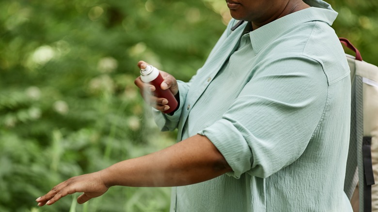 Woman spraying bug spray on arm