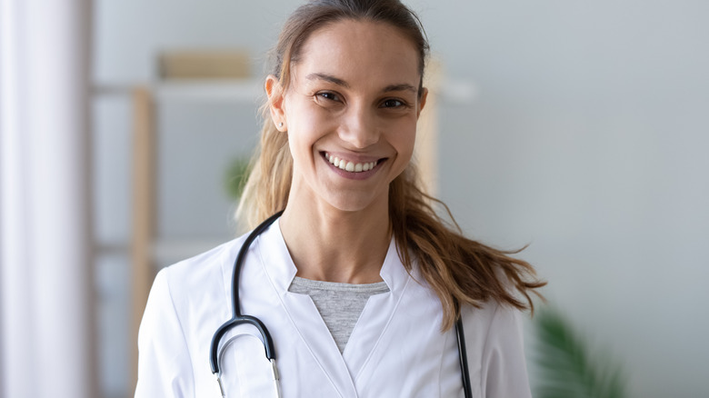 Woman smiling in white coat with stethoscope around her neck