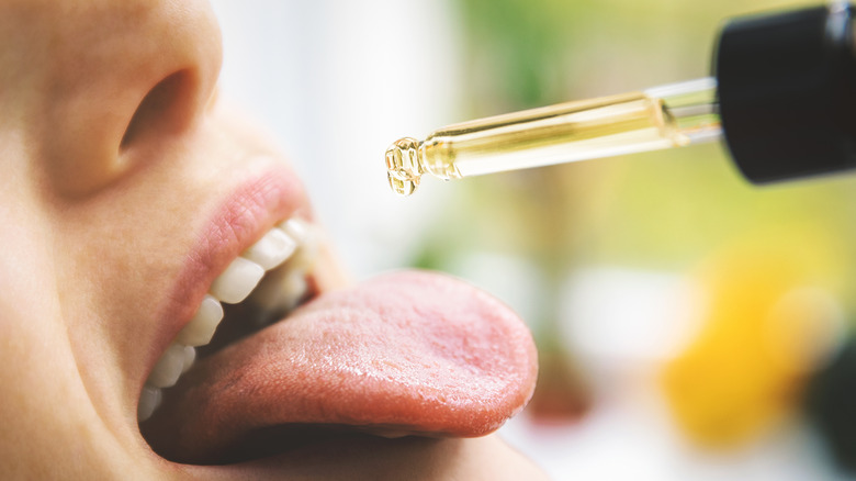 Person putting CBD oil on tongue