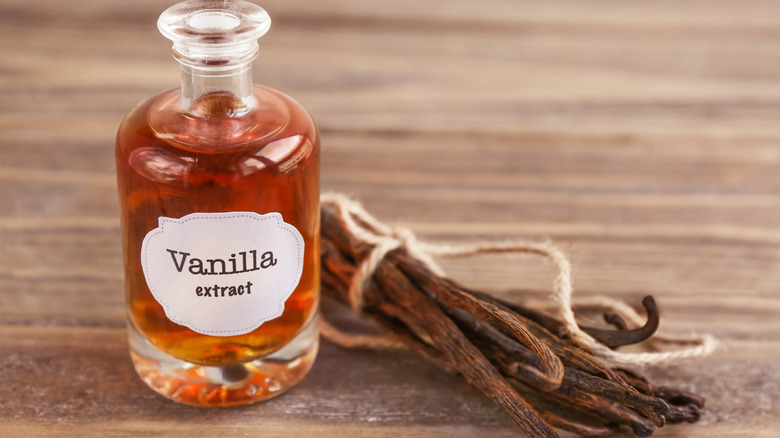 Vanilla extract in bottle with dried vanilla near it