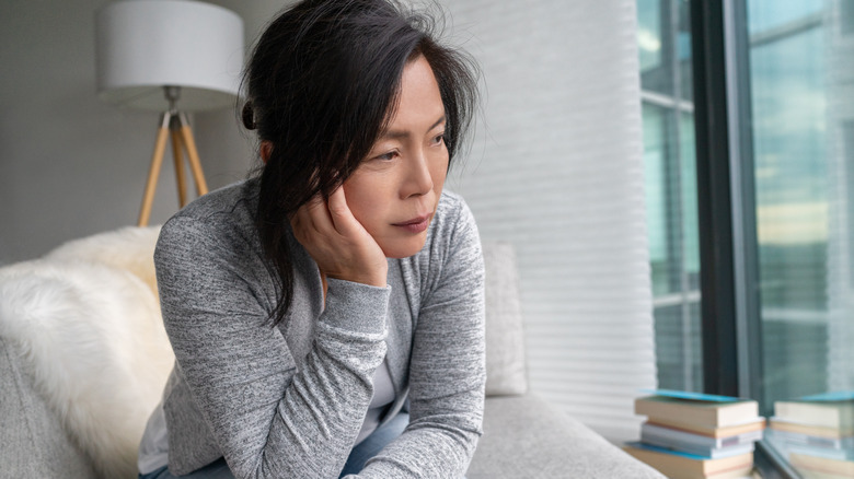 woman staring off while looking depressed on her couch