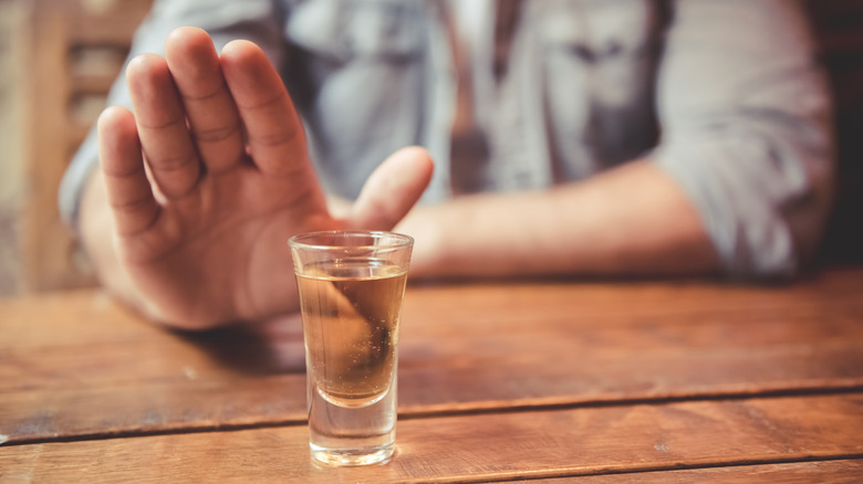 man holding up his hand to reject a shot of alcohol