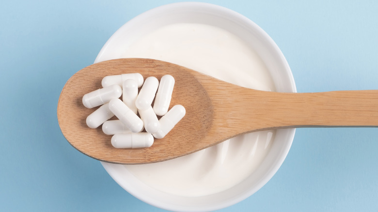Probiotic capsules on spoon over yogurt