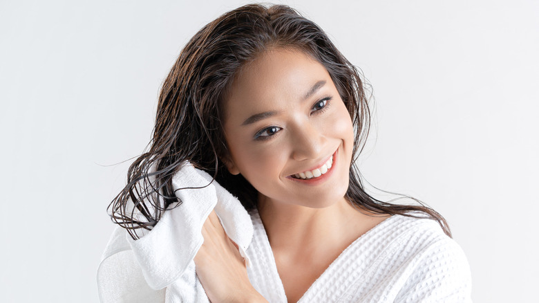 Young woman towel drying her hair in a robe 