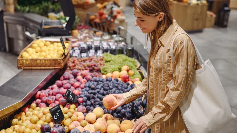 A young woman buying fruit at the grocery store.