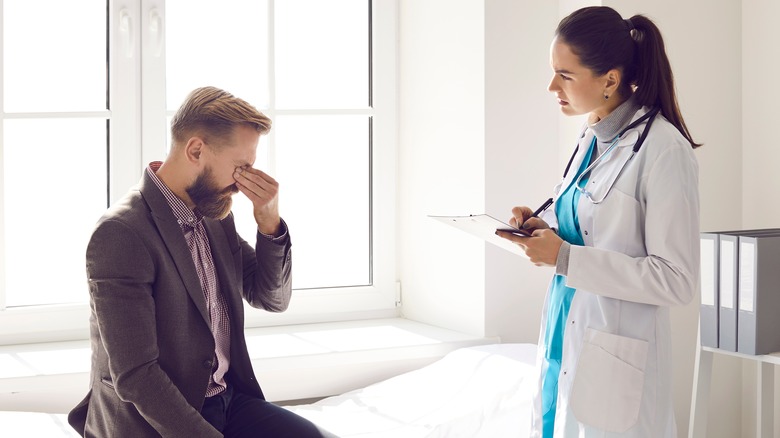 Man rubbing eyes in doctors office