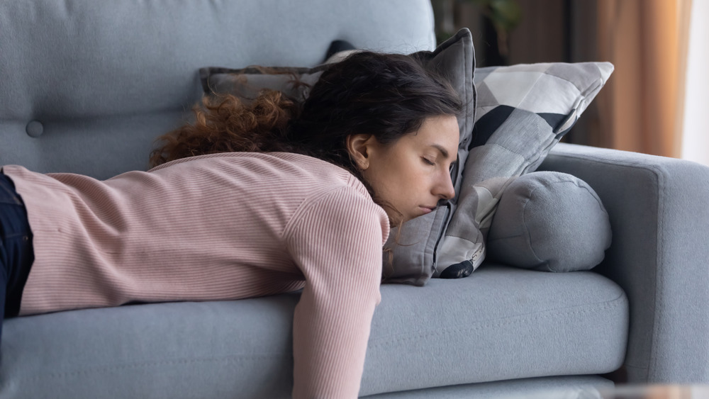 Exhausted stressed woman asleep facedown on couch