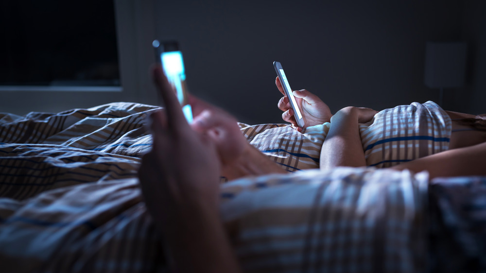 Couple looking at phones in bed