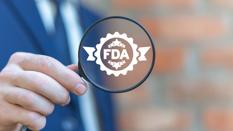 Person holding magnifying glass with FDA symbol