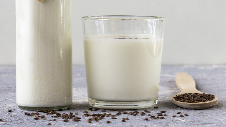 Glass of milk surrounded by flaxseeds