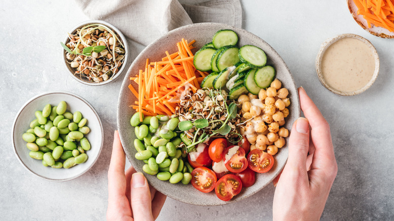 woman's hands holding a bowl of beans and vegetables