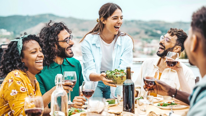 group of happy people dining in the summer