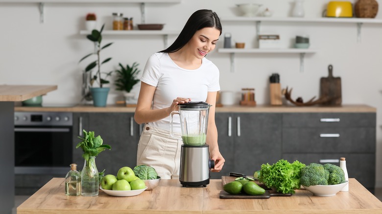 woman blending green smoothie