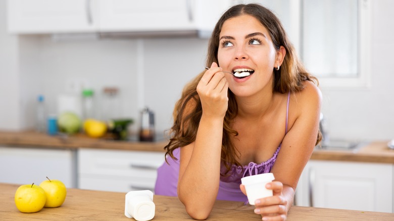 woman eating yogurt in her kitchen