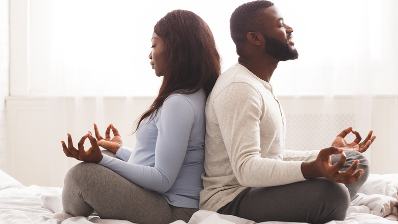 Couple seated back to back in meditation