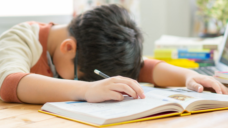 sleep deprived child fallen asleep on desk