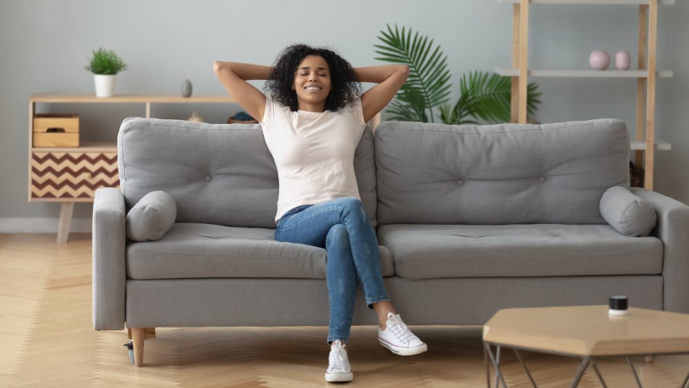 A young woman looking serene while sitting on her couch 